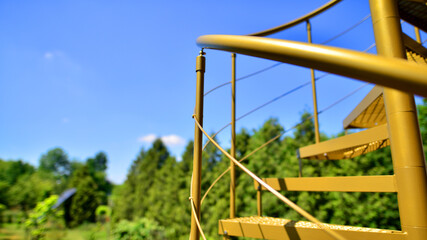 Winding spiral staircase outdoors. Metal curved stairs. Circular stairway on blue sky background.
