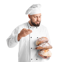 Male baker with loaves of fresh bread on white background