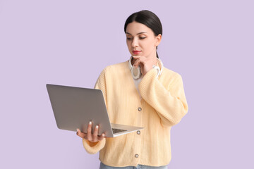 Thoughtful female programmer with laptop on lilac background