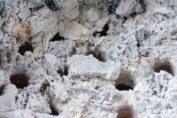In selective focus gray ashes in a Thai tradition brazier with a group of small holes inside for background backdrop 