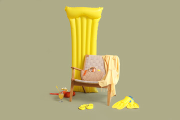 Chair, beach accessories and inflatable mattress on green background