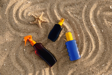 Bottles of sunscreen cream with starfish on sand at beach