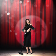 Beautiful singer performing in spotlight on stage against red curtain