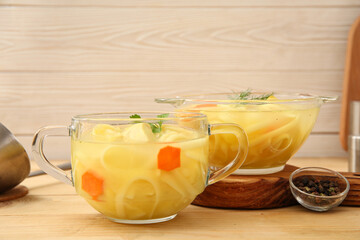 Pots of tasty chicken soup on wooden background