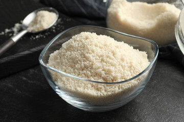 Fresh almond flour in bowl on dark table, closeup