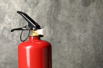 One red fire extinguisher on gray background, space for text