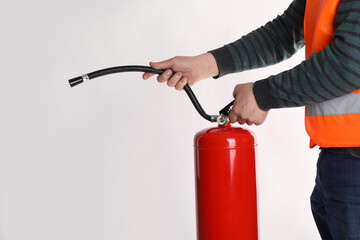 Man with fire extinguisher on light background, closeup