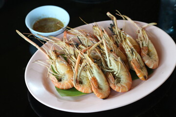 Grilled shrimp on a plate with dipping sauce at a restaurant