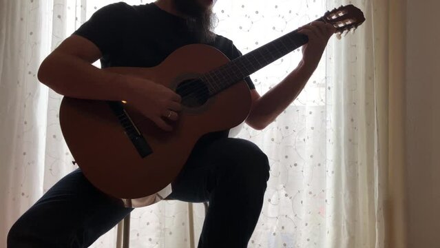 Chico tocando m&uacute;sica con una guitarra cl&aacute;sica o espa&ntilde;ola