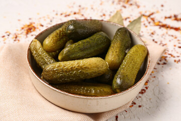 Bowl with tasty pickled cucumbers and spices on white background