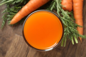 Healthy carrot juice in glass and fresh vegetables on wooden table, top view