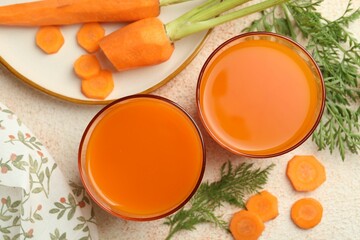 Healthy carrot juice in glasses and fresh vegetables on color textured table, top view