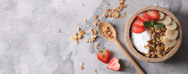 Tasty granola with yogurt, strawberry and banana on grey table, top view. Banner design with space for text