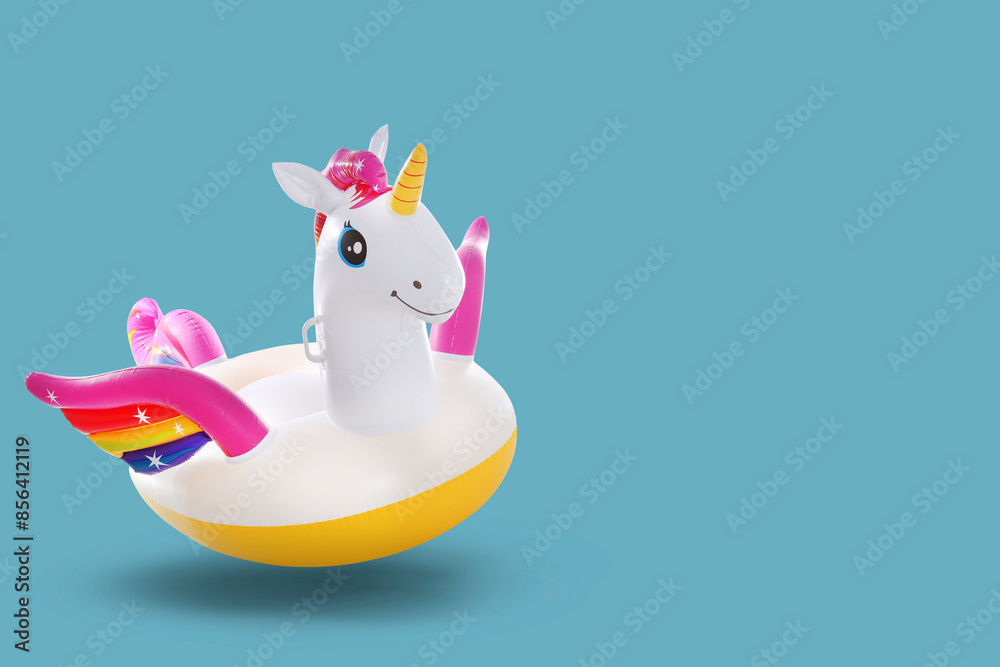 Wall mural Stylish inflatable unicorn shaped ring in air on color background. Space for text