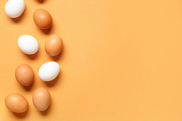 Raw chicken eggs on orange background