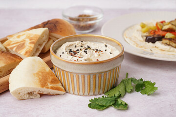 Bowl of tasty hummus with pita bread on white background