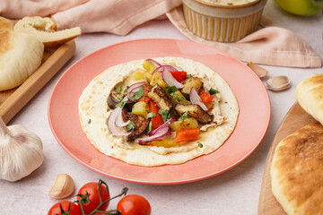 Plate of tasty pita bread with grilled vegetables and sauces on white background