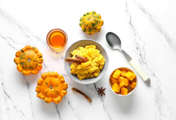 Bowl of tasty millet porridge with pumpkin and honey on white marble background