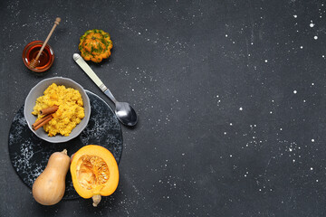 Bowl of tasty millet porridge with pumpkin and honey on black background
