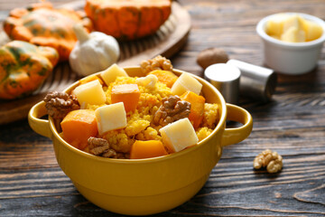 Pot of tasty millet porridge with pumpkin and cheese on wooden background
