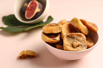 Bowl with sweet dried figs on pink background