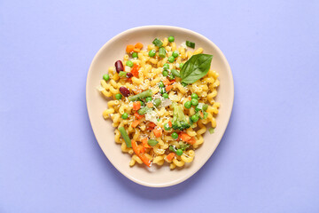 Plate with tasty pasta primavera on lilac background