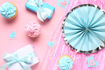 Delicious cupcakes with gift boxes and decorations on pink background. Gender reveal party concept