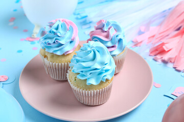 Plate with delicious cupcakes and decorations on blue background. Gender reveal party concept