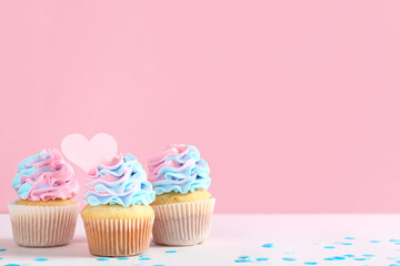 Delicious cupcakes with confetti on table against pink background. Gender reveal party concept