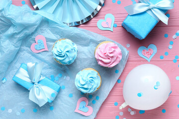 Delicious cupcakes with question marks, gift boxes and decorations on pink wooden background. Gender reveal party concept