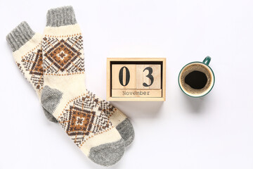 Warm socks with cube calendar and cup of coffee on white background