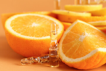Ampoules with vitamin C and oranges on beige background