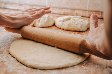 Hands rolling out dough with a rolling pin