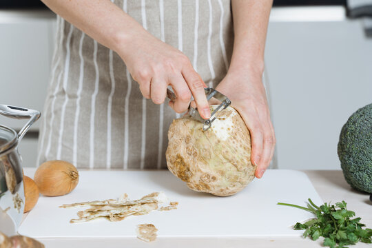 Woman peeling a celery root or celeriac in the kitchen