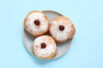 Plate with delicious donuts for Hanukkah celebration on color background