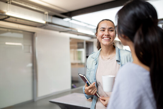 Aboriginal woman smiling while looking at her colleague in an office