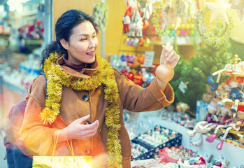 Portrait of smiling happy woman holding christmas ball in her hands on a street market