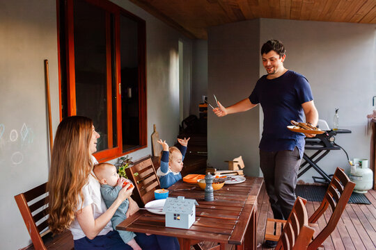 Aussie family having BBQ dinner of sausages on back deck of home
