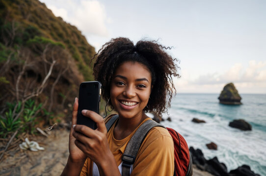 Woman holding a smartphone on a rocky coastline - Powered by Adobe
