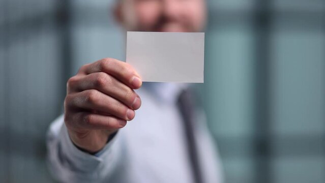 business man holding empty white business card in modern office building. Free blank copy space.