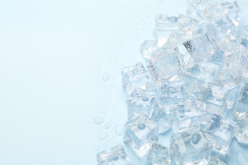 Crystal clear ice cubes on light blue background, flat lay. Space for text