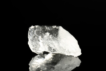 Piece of clear ice on black mirror surface