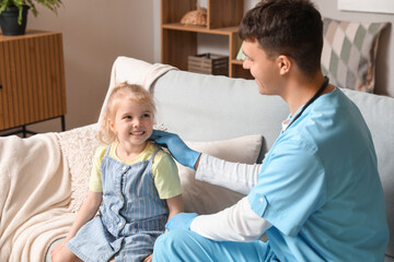 Obraz premium Male pediatrician examining little girl at home