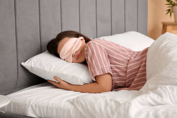 Pretty young woman with mask sleeping in bed