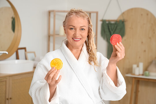 Mature woman with solid shampoo bars in bathroom