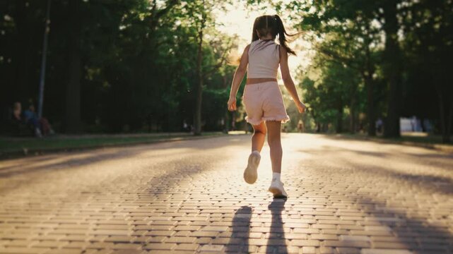 A childs silhouette joyfully walks on a brick path in a park, symbolizing adventure, beauty, bliss, freedom, joy, innocence, and youth amidst the tranquility of natures backdrop