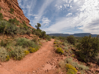 Hiking path along a high desert mountainside on a bright day with clouds.