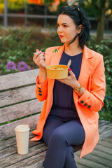 Businesswoman eating a healthy lunch outside the office in a city park, healthy lifestyle. Lunch is...