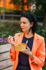Businesswoman eating a healthy lunch outside the office in a city park, healthy lifestyle. Lunch is a delicious salad - contains vitamins and is a dietary meal.  