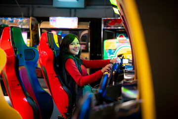 Young Latina woman smiling and playing arcade games in Akihabara, Tokyo, Japan, surrounded by...